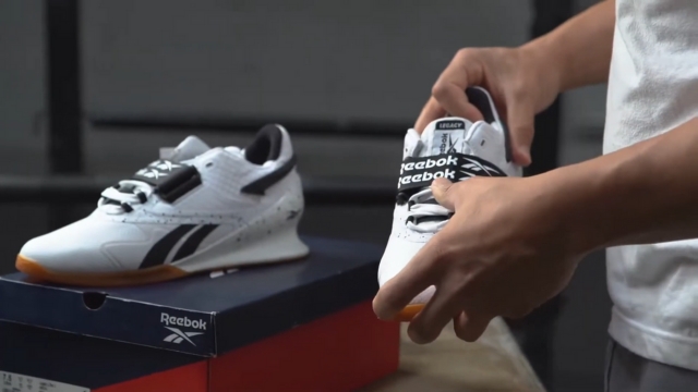 Muškarac drži Reebok Legacy Lifter II patike dok ih vadi iz kutije